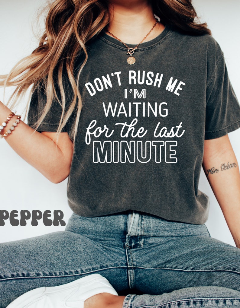 May include: A dark gray t-shirt with the text "Don't rush me I'm waiting for the last minute" in white lettering.