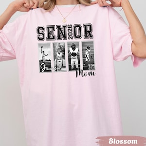 May include: A light pink t-shirt with the words "SENIOR 2026" in black block letters. Below the text are four black and white photos of football players. The name "James" and the word "Mom" are below the photos. The shirt is labeled "Blossom".