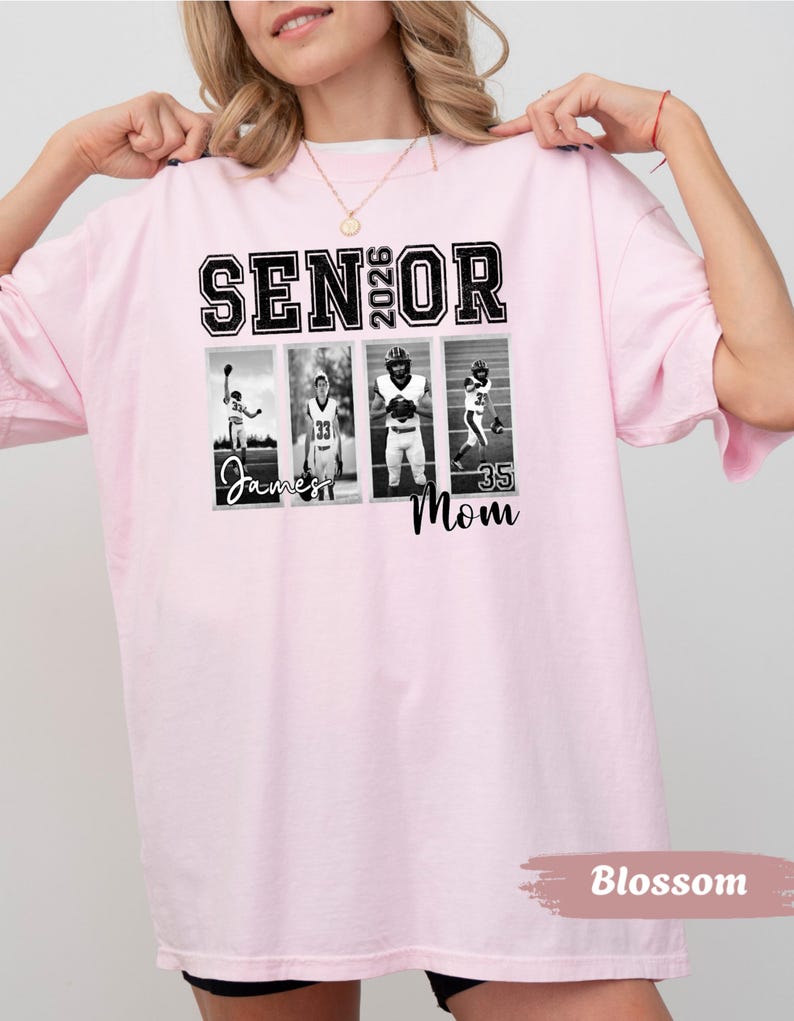 May include: A light pink t-shirt with the words "SENIOR 2026" in black block letters. Below the text are four black and white photos of football players. The name "James" and the word "Mom" are below the photos. The shirt is labeled "Blossom".