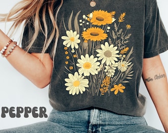 May include: A dark gray t-shirt with a vintage floral print featuring yellow and white daisies. The shirt has a crew neck and short sleeves.