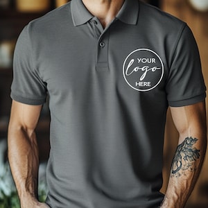 May include: A charcoal gray polo shirt with a three-button placket and short sleeves. The shirt features a white circular logo that says "YOUR logo HERE". The shirt is made of a soft, breathable fabric.