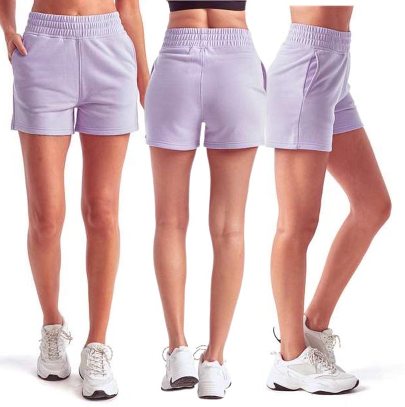 May include: Light purple athletic shorts with an elastic waistband and pockets. The shorts are made of a soft material and are shown from multiple angles. The shorts are paired with white athletic shoes.