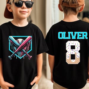 May include: A black t-shirt featuring a front graphic of two crossed baseball bats over a baseball inside a light blue square with a dripping paint effect. The back displays the name OLIVER in light blue and the number 8 with a donut pattern.