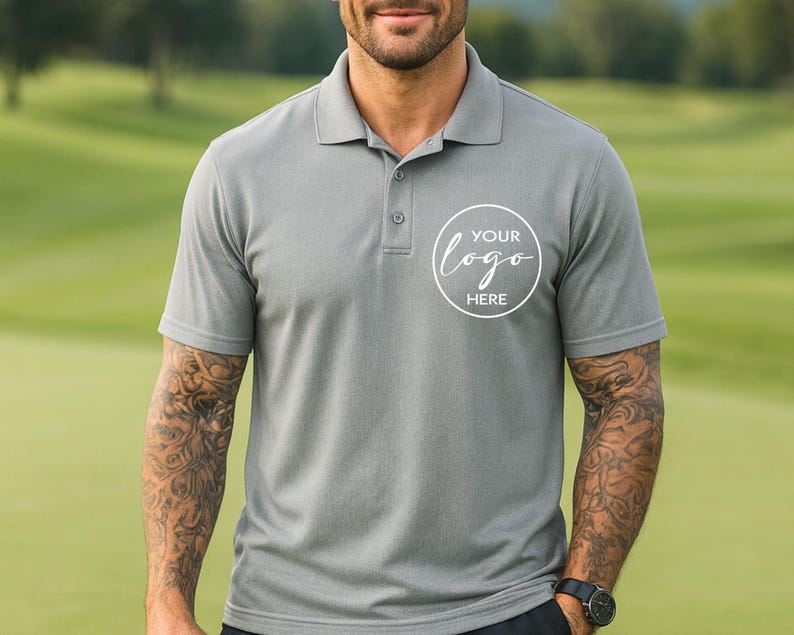 May include: Grey polo shirt with a three-button placket and short sleeves. The shirt features a white circular logo with the text "YOUR logo HERE". The model is wearing a black watch.