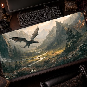 May include: A rectangular desk mat featuring a detailed landscape illustration of a dark dragon flying over a winding river valley. The scene includes towering mountains, dense evergreen forests, and a meadow with wildflowers under a soft light.