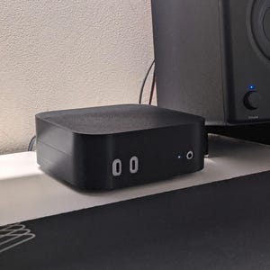 Puede incluir: Un amplificador de audio rectangular negro con una pequeña pantalla que muestra el número "00".