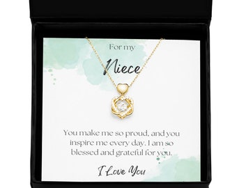May include: A gold necklace with a heart-shaped pendant and a small clear stone in the center. The necklace is in a black box with a white card that says "For my Niece" and "You make me so proud, and you inspire me every day. I am so blessed and grateful for you. I Love You."