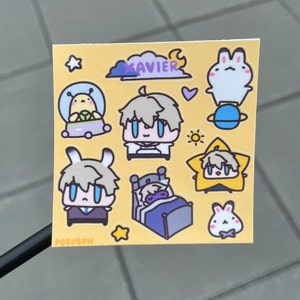 Op de afbeelding: Een set gele, witte en blauwe stickers met een cartoonfiguur genaamd "Xavier". De stickers bevatten een figuur in een ruimteschip, een figuur die slaapt in een bed, een figuur in een ster en een konijn.