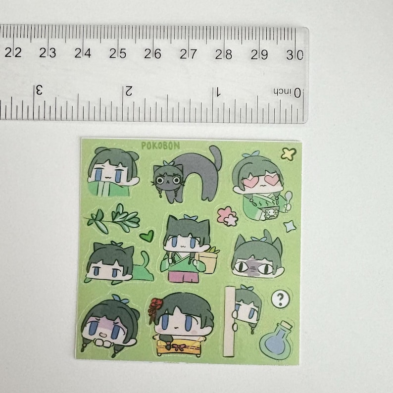 May include: A sheet of stickers featuring cartoon characters with green hair and cat ears, along with a gray cat. The stickers include various poses and expressions, with the word "POKOBON" at the top. The ruler shows the stickers are approximately 3 inches wide.