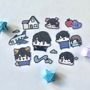Op de afbeelding: Een set stickers met cartoonfiguren met verschillende uitdrukkingen. De stickers zijn op een witte achtergrond met origami-sterren in blauw en paars. De stickers bevatten een huis, een vliegtuig, een hart met het woord "Caleb" erop en verschillende personages met verschillende uitdrukkingen.