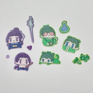 May include: A collection of colorful stickers featuring anime-style characters in various poses. The stickers include figures in green and purple, along with a staff, a heart, and a potion bottle. These stickers are ideal for decorating notebooks, laptops, or other items.