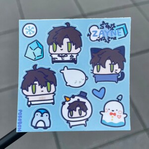 Op de afbeelding: Een vel met blauwe stickers met verschillende cartoonfiguren, waaronder een pingu&iuml;n, een sneeuwpop, een zeehond en een kat. De stickers zijn allemaal in chibi-stijl en hebben een schattige en fantasierijke esthetiek. De tekst "ZAYNE" en "POKOBON" staan ook op het vel.
