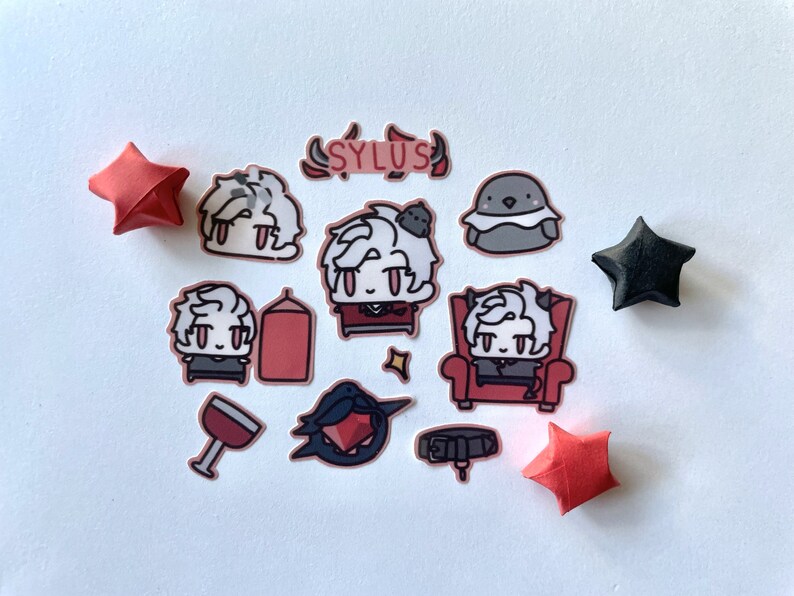 Op de afbeelding: Een set van 11 stickers met een cartoonfiguur met wit haar en rode ogen. De stickers zijn op een witte achtergrond en bevatten een banner met de tekst "SYLUS".
