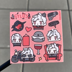 Op de afbeelding: Een roze stickervel met verschillende illustraties van een personage met wit haar en rode ogen. Het personage wordt afgebeeld in verschillende poses en settings, waaronder op een motor rijden, op een troon zitten en een glas wijn vasthouden. Het stickervel bevat ook een hart, een vogel, een kaars en een pistool. De tekst "SYLUS" en "POKOBON" is zichtbaar op het stickervel.