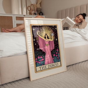 May include: Framed art print featuring a woman in a pink gown with a gold halo, holding a globe. The artwork is set against a dark background with stars and flowers, with the text "THE DISCO" at the bottom.