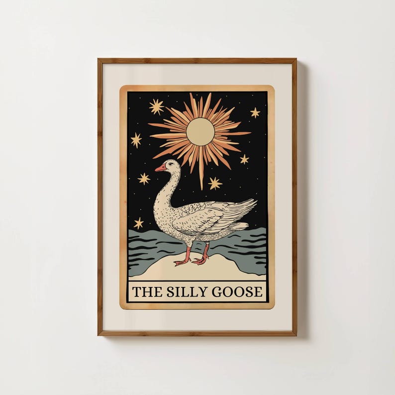 May include: Framed art print with a goose illustration. The image shows a goose on a rock, set against a backdrop of a sun and stars. The text "THE SILLY GOOSE" is at the bottom. The frame is brown.