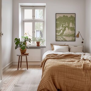 Pu&ograve; includere: Una camera da letto con un letto dotato di una trapunta testurizzata color senape e cuscini a righe, una stampa incorniciata di un salice piangente verde sulla parete, un piccolo tavolino in legno con una pianta monstera e una finestra bianca.