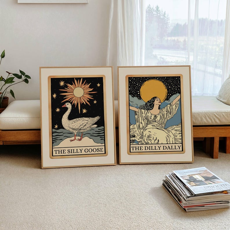 May include: Two framed art prints with light wood frames. One features a goose with the text "THE SILLY GOOSE". The other shows a woman with arms raised and the text "THE DILLY DALLY". Both have a vintage aesthetic with a cream background.