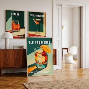 Op de afbeelding: Drie ingelijste kunstprints met cocktailillustraties. De prints tonen een Negroni, Espresso Martini en Old Fashioned. Elke print heeft een teal achtergrond met de cocktailnaam in het wit. De Old Fashioned print bevat een kers en een sinaasappelschijfje als garnering.