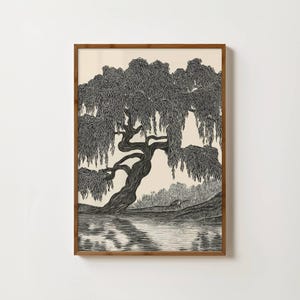 May include: Black and white art print of a weeping willow tree by a lake. The tree's branches cascade down, and its reflection is visible in the water. The artwork is framed in a wooden frame.