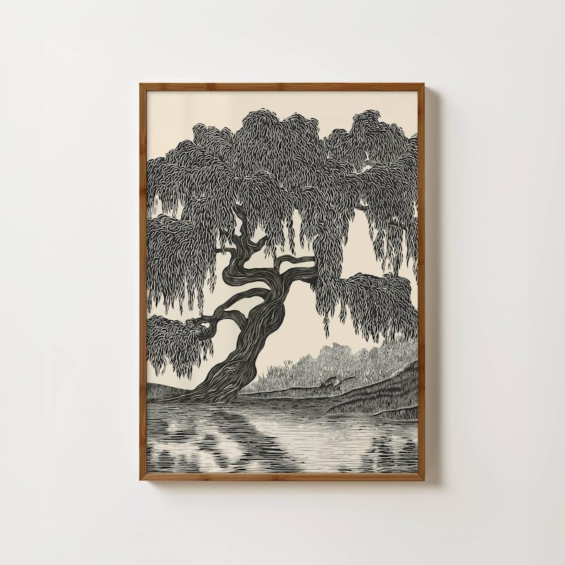 May include: Black and white art print of a weeping willow tree by a lake. The tree's branches cascade down, and its reflection is visible in the water. The artwork is framed in a wooden frame.