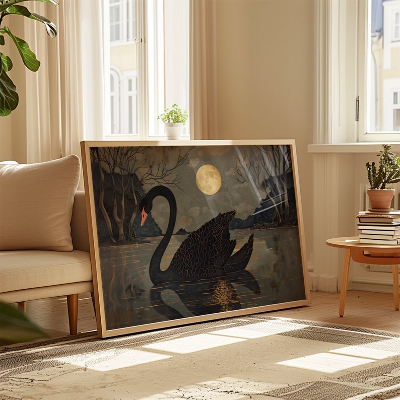 May include: A framed print of a black swan swimming in a dark blue lake under a full moon. The swan is facing left and has a long neck and a black body. The moon is a pale yellow color and is in the upper right corner of the image. The background is a dark blue color with a few trees in the distance.