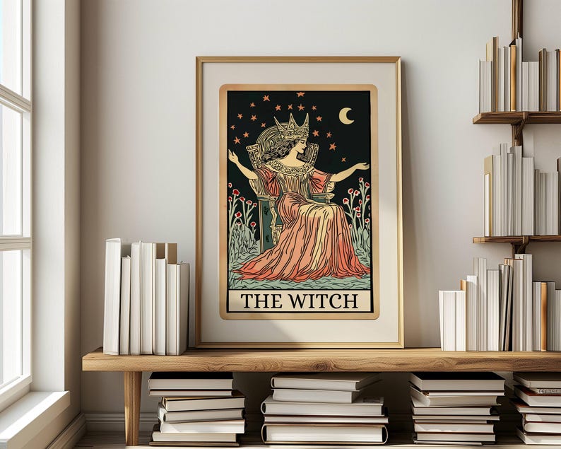 May include: Framed art print of a tarot card titled "The Witch." The illustration features a woman in a crown and gown, seated on a throne against a starry night sky. The artwork is in a gold frame and displayed on a wooden shelf.