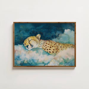Peut inclure: Peinture à l'aquarelle encadrée d'un guépard endormi. Le guépard a un pelage beige avec des taches noires et repose sur un lit de nuages ​​bleu clair et duveteux. L'arrière-plan est bleu foncé avec des paillettes dorées.