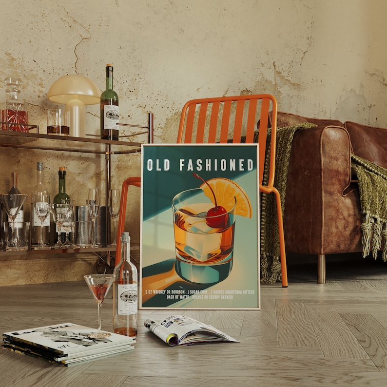 Op de afbeelding: Poster met een "Old Fashioned" cocktail met een kers en sinaasappelschijfje. De poster leunt tegen een oranje stoel, met een leren bank en een barwagen op de achtergrond. Een martiniglas en tijdschriften liggen op de grond.