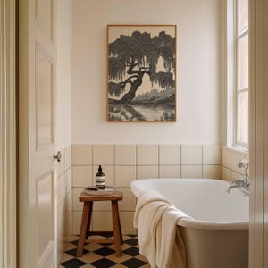 May include: A bathroom scene featuring a framed black and white tree print above a white bathtub. A small wooden stool holds a bottle and a brush. The floor has a black and white checkered pattern.