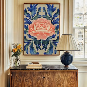 May include: A framed print of a pink peony flower with blue and green leaves on a white background. The print is hanging on a wall above a wooden dresser with a black marble top.
