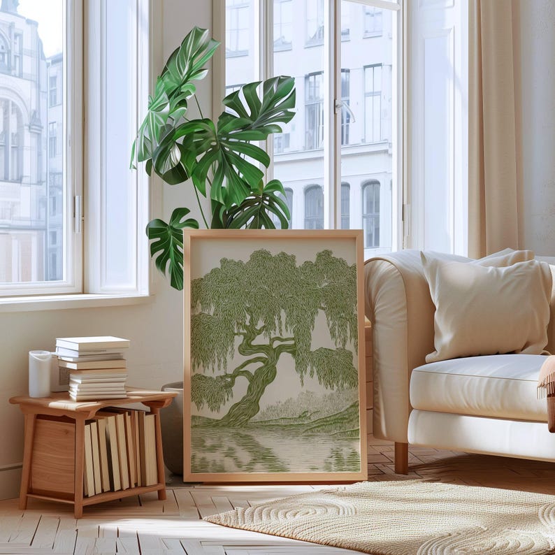 Pu&ograve; includere: Una stampa artistica incorniciata che presenta un'illustrazione dettagliata a inchiostro verde di un grande salice piangente con lunghi rami pendenti sopra uno specchio d'acqua calmo, in una cornice di legno chiaro poggiata a terra.
