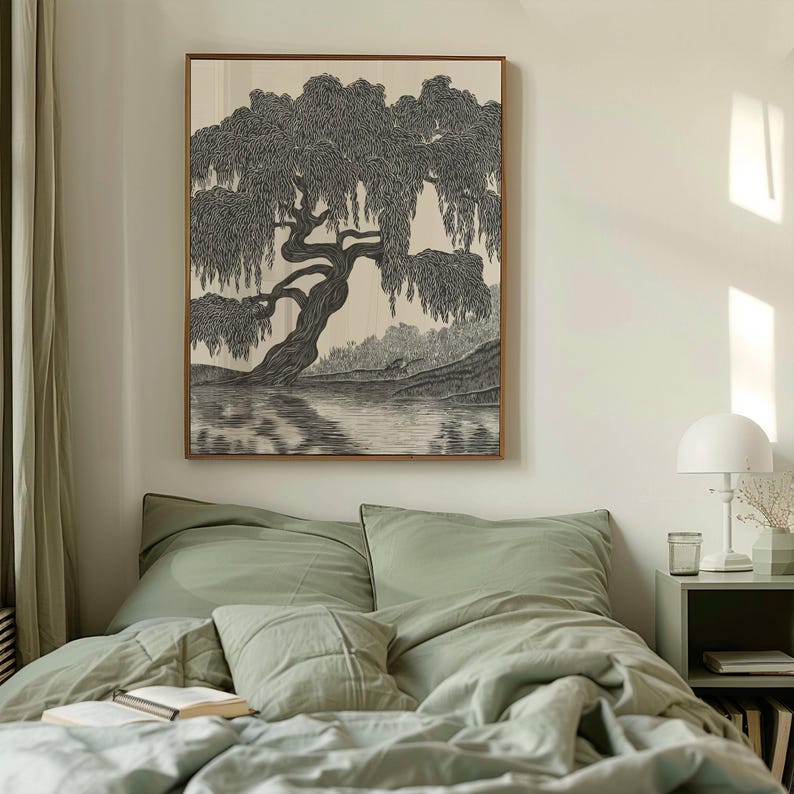 May include: A framed black and white illustration of a weeping willow tree over a body of water. The artwork is displayed above a bed with sage green bedding. The room has a minimalist aesthetic with a white lamp and side table.