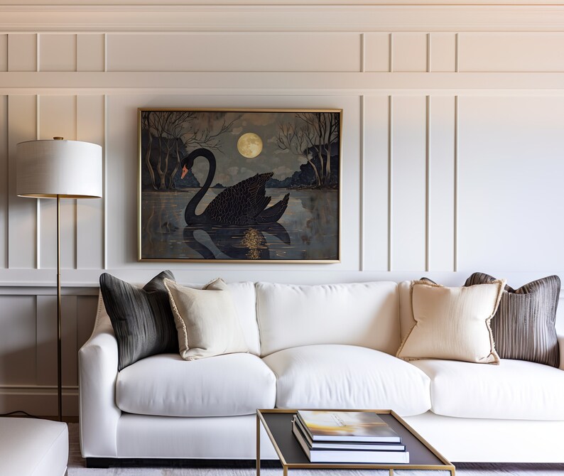 May include: A white sofa with black and beige throw pillows sits in front of a wall with wainscoting. A framed painting of a black swan on a lake with a full moon hangs above the sofa. A gold floor lamp stands to the left of the sofa.