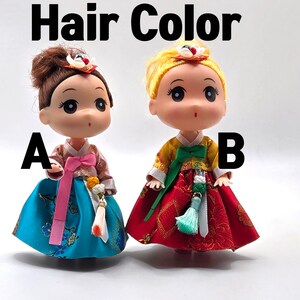 May include: Two dolls wearing traditional Korean hanbok dresses. The doll on the left has brown hair and a blue dress with pink accents. The doll on the right has blonde hair and a red dress with green accents. The dolls are labeled A and B.
