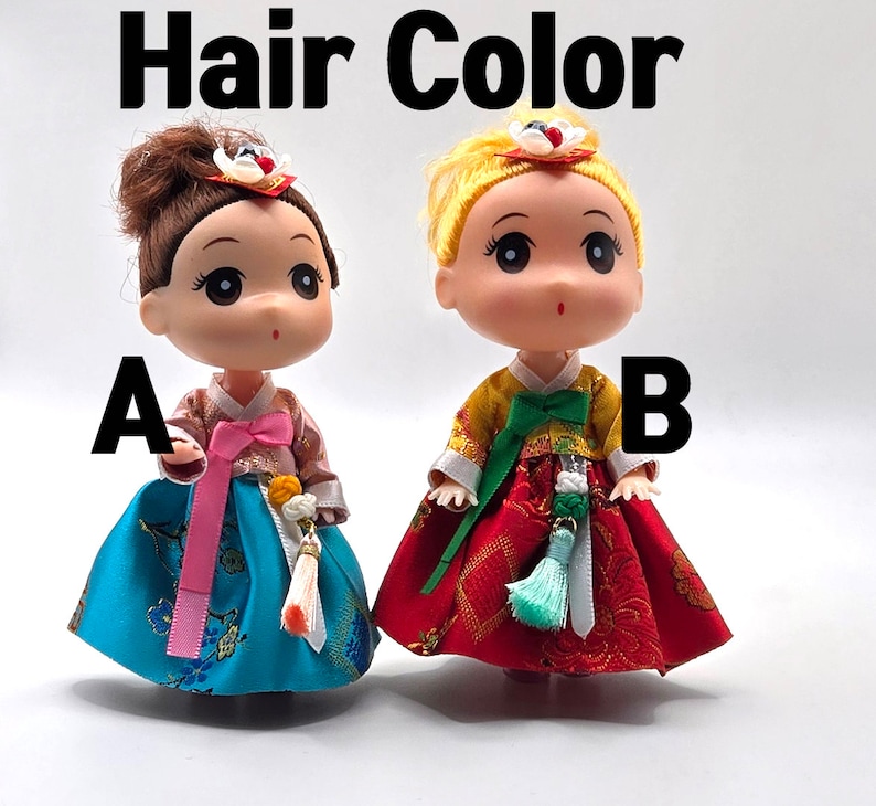 May include: Two dolls wearing traditional Korean hanbok dresses. The doll on the left has brown hair and a blue dress with pink accents. The doll on the right has blonde hair and a red dress with green accents. The dolls are labeled A and B.