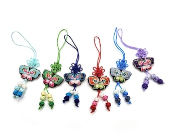 May include: Five colorful butterfly charms with knotted strings. Each charm features a different color combination of blue, green, red, and purple.