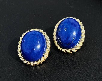 Könnte beinhalten: Ein Paar goldfarbene Ohrringe mit blauen Edelstein-Cabochons. Die Ohrringe haben ein seilartiges Design um die Ränder der Steine.