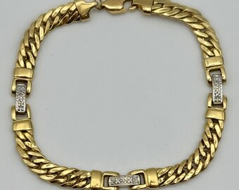 May include: A gold-toned bracelet with a curb chain design. The bracelet features rectangular links with small, clear stones. The clasp and connecting links are also gold-toned. The bracelet is approximately 7.5 inches in length.