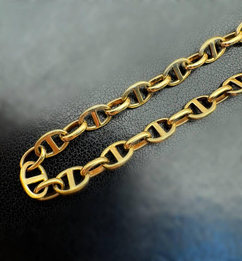 May include: A gold chain necklace with a mariner link design. The chain is made of thick, solid links.