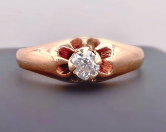 May include: A rose gold ring featuring a single round brilliant-cut clear gemstone set in the center. The metal band is designed with a carved floral motif surrounding the stone, creating a textured, petal-like setting for the central gem.