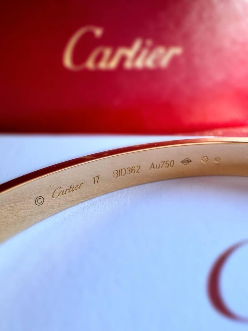 May include: A gold Cartier bracelet with the inscription 'Cartier 17 BID362 Au750' on the inside.