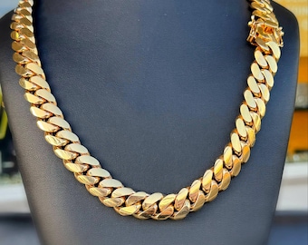 Peut inclure: Un collier chaîne gourmette de couleur or exposé sur un mannequin noir. Le collier présente des maillons épais et imbriqués et un fermoir sécurisé. La chaîne est de couleur or vif et brillante.