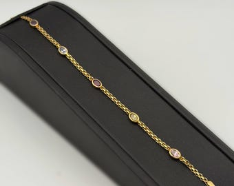 May include: A gold chain bracelet featuring five evenly spaced, bezel-set oval gemstones in various colors including purple, blue, red, yellow, and pink. The bracelet is constructed with a delicate link chain design and a polished gold finish.