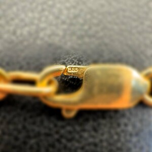 May include: Close-up of a gold chain with a clasp marked "585".