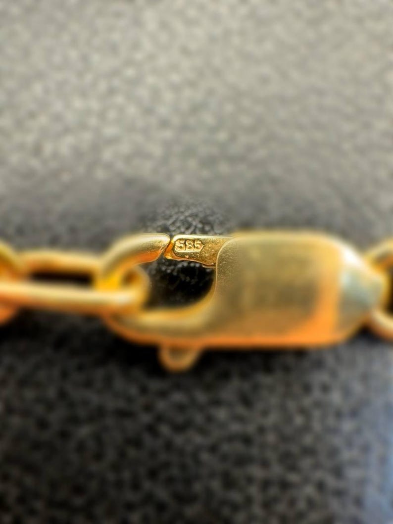 May include: Close-up of a gold chain with a clasp marked "585".