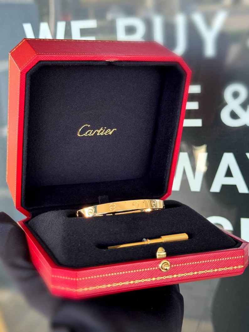 May include: A gold Cartier love bracelet in a red box with the Cartier logo and a small gold screwdriver.