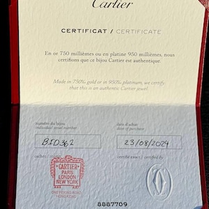 May include: A white certificate with the text 'Cartier' in red at the top. The text 'CERTIFICAT / CERTIFICATE' is printed in black below the Cartier logo. The certificate is for a Cartier jewel made in 750% gold or 950% platinum. The certificate has a serial number 'BID 362' and a purchase date of '23/08/2024'. The certificate is stamped with the Cartier logo and the text 'CARTIER PARIS LONDON NEW YORK ONE PEKING ROAD HONG KONG'. The certificate also has the number '8887709' printed on it. The text 'Printed in France' is printed in the bottom right corner of the certificate.