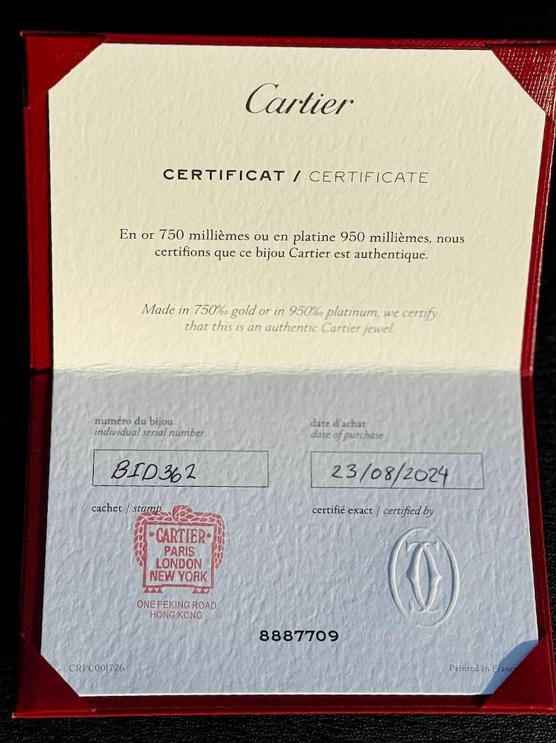 May include: A white certificate with the text 'Cartier' in red at the top. The text 'CERTIFICAT / CERTIFICATE' is printed in black below the Cartier logo. The certificate is for a Cartier jewel made in 750% gold or 950% platinum. The certificate has a serial number 'BID 362' and a purchase date of '23/08/2024'. The certificate is stamped with the Cartier logo and the text 'CARTIER PARIS LONDON NEW YORK ONE PEKING ROAD HONG KONG'. The certificate also has the number '8887709' printed on it. The text 'Printed in France' is printed in the bottom right corner of the certificate.