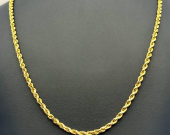 Peut inclure: Un collier chaîne de corde de couleur or présenté sur un mannequin noir. Le collier présente un motif de corde torsadée et est fait d'un matériau brillant et réfléchissant. Un bijou classique.